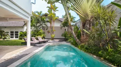 a swimming pool in the backyard of a house with palm trees at Villa Merta Sari 8 by Villa Finder in Seminyak