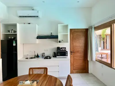 a kitchen with white cabinets and a wooden table at 1BR Tropical Villa With Pool - Canggu - Berawa in Canggu