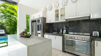 a kitchen with white cabinets and a counter top at Villa Merta Sari 10 by Villa Finder in Seminyak