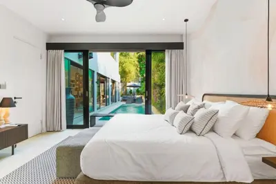 a bedroom with a large white bed and a pool at Luxury Villa in Berawa Beach 3BR - Canggu in Canggu