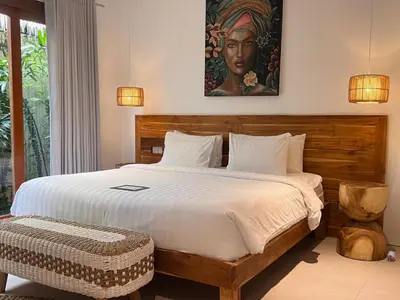 a bedroom with a large bed with a painting on the wall at villa Pacha 2 in Seminyak