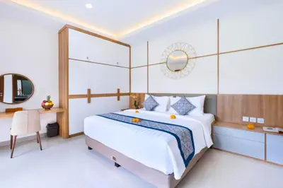 a bedroom with a large white bed and a desk at Zelene Elegant 3 BR Private Pool Villa in Seminyak