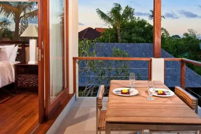 a wooden table with two plates of food on a balcony at Calista Peaceful 4 BR Private Pool Villa in Canggu