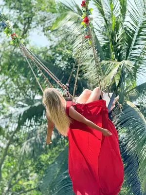 a woman sitting in a red dress on a swing at Bali Swing with Buggy adventure and white water Rafting in Pesanggaran