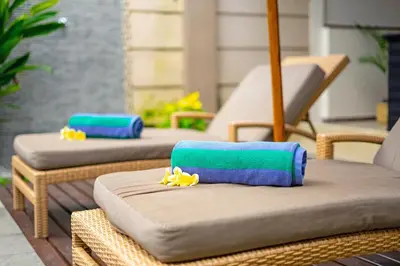 three wicker chairs with towels on them on a patio at Villa Alamanda, central location and close to restaurants in Seminyak