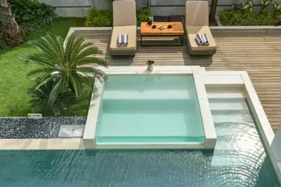 a swimming pool with two chairs and a table at Tanaya Luxury 4 BR Private Pool Villa in Canggu