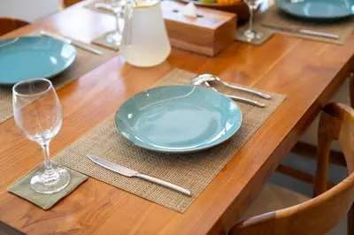 a wooden table with blue plates and a glass at Villa Hattala - Luxury Modern Villa in Prime Berawa with Air-Conditioned Living Space in Canggu