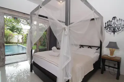 a bedroom with a canopy bed and a swimming pool at Bamboo Moon Villas in Sanur