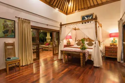 a bedroom with a canopy bed and a wooden floor at Andina Spacious Garden 4 BR Private Pool Villa in Seminyak