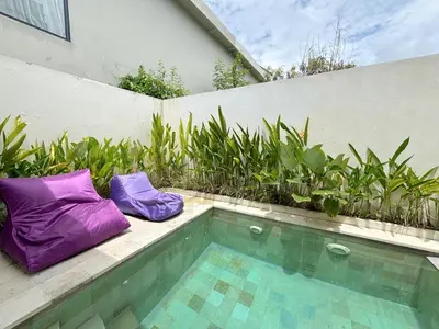 two purple pillows sitting next to a swimming pool at Villa Lilla and Sauna in Canggu