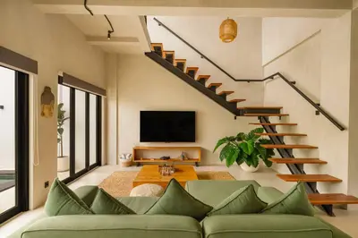 a living room with a green couch and stairs at Modern 1BR Villa with Private Pool in Kerobokan