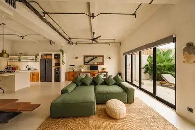 a living room with a green couch and a kitchen at Modern 1BR Villa with Private Pool in Kerobokan