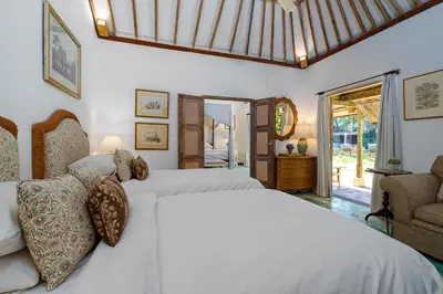 a bedroom with two white beds and a chair at The Orchard house Bali by Puri Asia in Seminyak