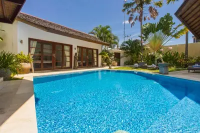 a swimming pool in front of a house at Philana Cozy 3 BR Private Pool Villa in Seminyak