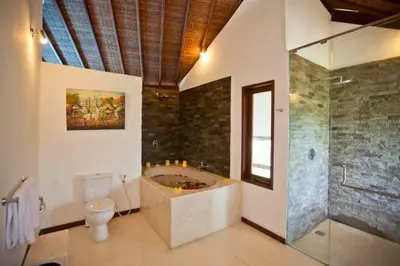 a bathroom with a tub and a toilet and a shower at Philana Cozy 3 BR Private Pool Villa in Seminyak