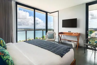 a bedroom with a bed and a desk with a television at Santos Cliff View Jimbaran in Jimbaran