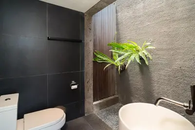 a bathroom with a toilet and a plant on the wall at Santos Cliff View Jimbaran in Jimbaran