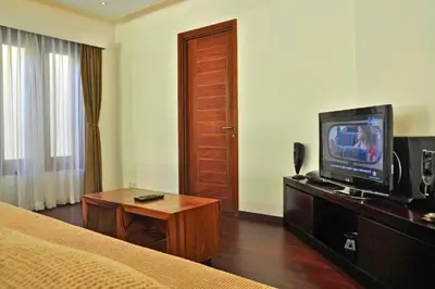 a hotel room with a bed and a television at Fidela Comfortable 3 BR Private Pool Villa in Seminyak