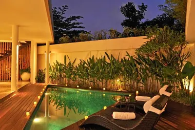 a swimming pool with chairs and a table next to a house at Fidela Comfortable 3 BR Private Pool Villa in Seminyak