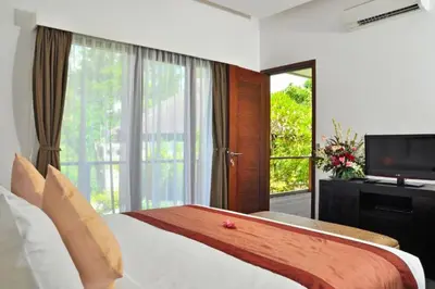 a bedroom with a bed and a tv and a window at Fidela Comfortable 3 BR Private Pool Villa in Seminyak
