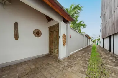 an empty courtyard of a white building with a wooden door at Tropical 2BR Pool Villa near Seminyak & Canggu in Kerobokan