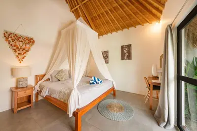 a bedroom with a bed with a mosquito net at Tropical 2BR Pool Villa near Seminyak & Canggu in Kerobokan