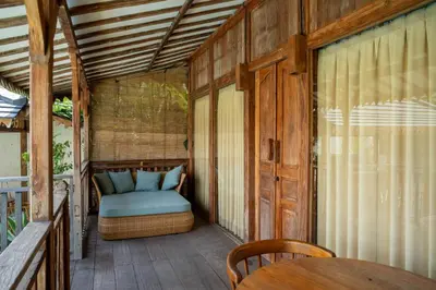 a porch with a bed and a table on a deck at Tuluscoliving Villa Kuta 3, 3 Bedroom & 3 Bathroom in Ngurah Rai International Airport