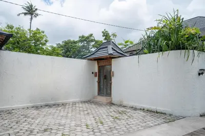 a white wall with a door and a fence at Tuluscoliving Villa Kuta 3, 3 Bedroom & 3 Bathroom in Ngurah Rai International Airport