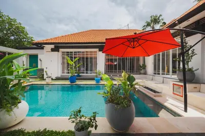 a pool with a red umbrella next to a house at Xxtra Villa in Seminyak