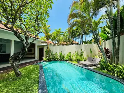 a swimming pool in front of a house with trees at Kubu Manggala Villas Seminyak in Seminyak