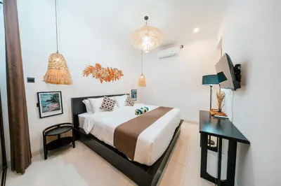 a bedroom with a bed and a desk and a television at Villa Gadang in Kerobokan
