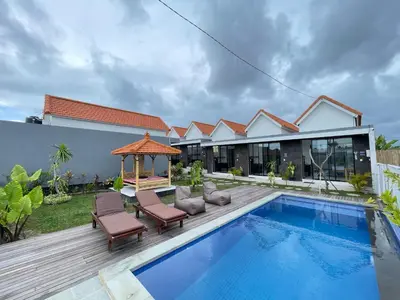 a villa with a swimming pool and a gazebo at Gede Awan Guesthouse in Kerobokan
