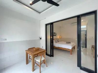 a bedroom with a bed and a table at Gede Awan Guesthouse in Kerobokan