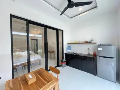a kitchen with a refrigerator and a table in it at Gede Awan Guesthouse in Kerobokan