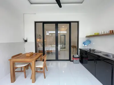 a kitchen with a wooden table and chairs in it at Gede Awan Guesthouse in Kerobokan
