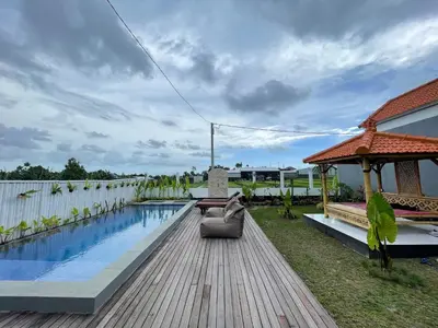 a backyard with a wooden deck and a swimming pool at Gede Awan Guesthouse in Kerobokan