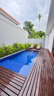 a backyard with a swimming pool and a wooden deck at Villa Harmaka in Kerobokan