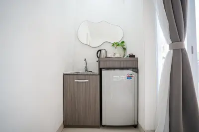 a small kitchen with a refrigerator and a mirror at Harmony Beach Suite in Seminyak