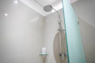 a shower with a shower head in a bathroom at Harmony Beach Suite in Seminyak