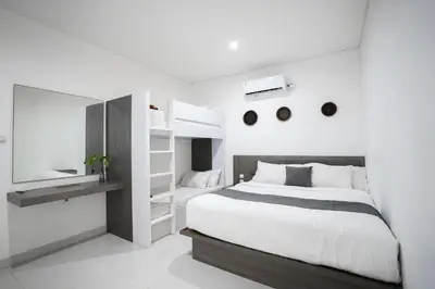 a white bedroom with a large bed and a mirror at Harmony Beach Suite in Seminyak
