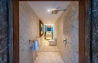 a hallway of a bathroom with a toilet and a sink at Tides Seminyak in Seminyak