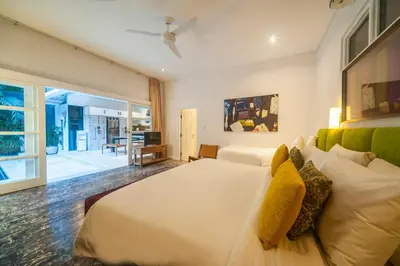 a bedroom with a large white bed and a living room at Tides Seminyak in Seminyak