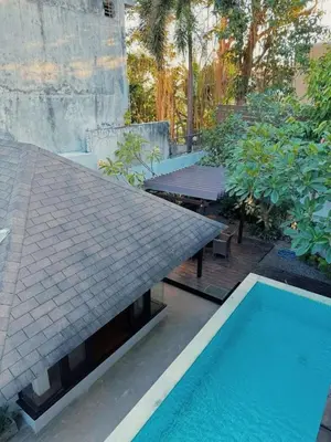 a swimming pool next to a house with a roof at Villa Jovino - Jameja By Island Villa Management in Kerobokan