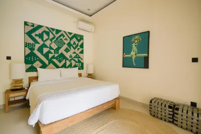 a bedroom with a white bed and a painting on the wall at Villa Lediana - 3BR Private pool in Canggu