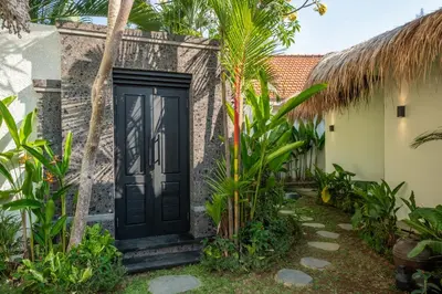 a black door in front of a house with palm trees at Villa Lediana - 3BR Private pool in Canggu