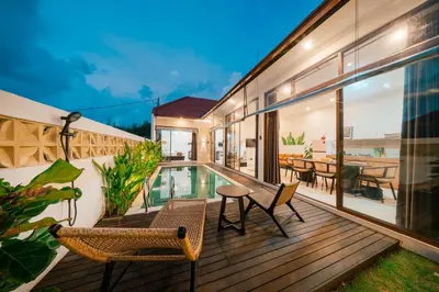 an outdoor deck with chairs and a swimming pool at Villa Tyaga in Kerobokan