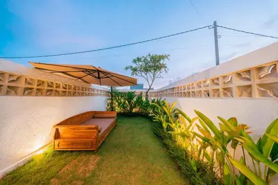 a patio with a bench and an umbrella at Villa Tyaga in Kerobokan