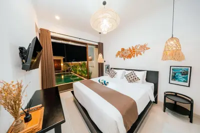 a bedroom with a bed and a tv and a window at Villa Tyaga in Kerobokan