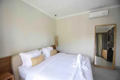 a bedroom with a white bed and a mirror at Villa Marina in Canggu