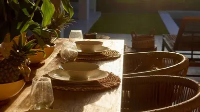 a wooden table with plates and bowls and glasses on it at Villa Marina in Canggu